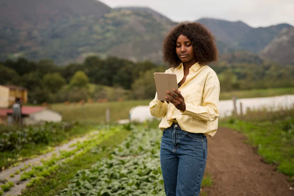 une jeune femme debout dans un potager avec sa tablette, Agrivoltaïsme