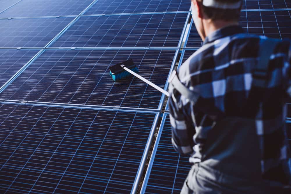 uin homme vu de dos qui fait un nettoyage toiture photovoltaique
