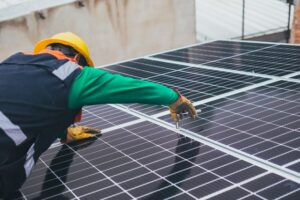 un professionnel vu de dos qui installe des panneaux solaires, installation panneaux photovoltaiques